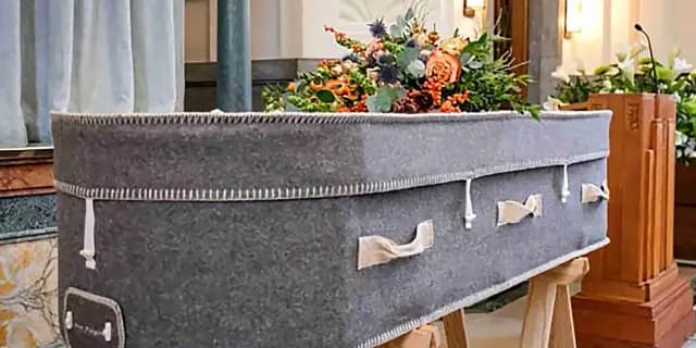 Fabric-covered coffin with flowers in a chapel setting