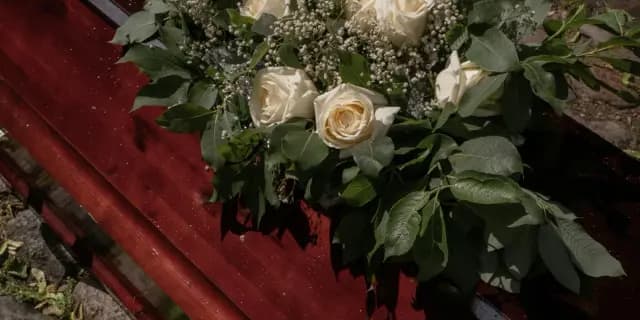 White roses resting on a polished timber coffin